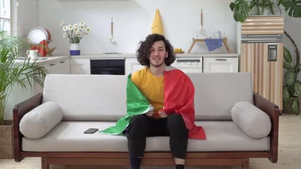 Blije Italiaanse fan verheugt zich over de overwinning. Een man met de vlag van Italië kijkt thuis naar sport op tv — Stockvideo