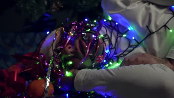 Een man slaapt onder een boom in een bloemenslinger. Grappig Nieuwjaar of Kerstmis — Stockvideo