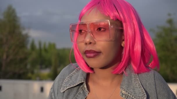Joven mujer africana negra pensativa con el pelo rosa al aire libre. Juventud moderna — Vídeos de Stock