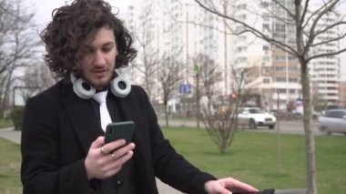 Genç bir erkek öğrenci ya da iş adamı akıllı telefona bakar ve duygusal olarak zaferle ya da başarıyla sevinir.