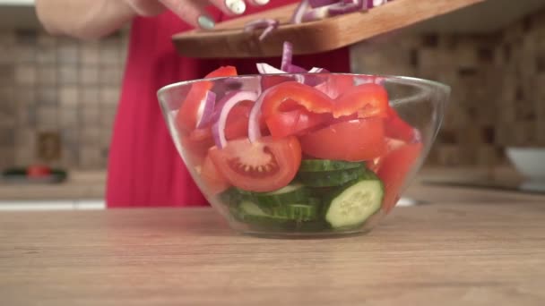 Eine Frau in der Küche bereitet in Zeitlupe einen Gemüsesalat in einer Glasschale zu — Stockvideo