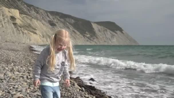 小女孩在海滩上把石头扔进海里 — 图库视频影像