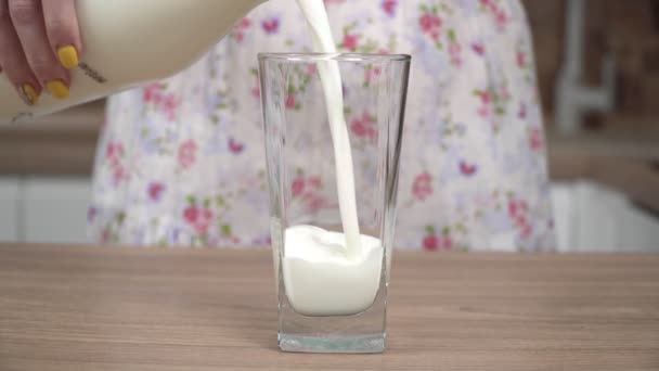 Egy nő a konyhában tejet önt egy üvegből egy pohárba. — Stock videók