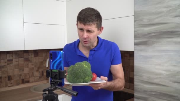 Шеф-повар-блогер снимает видео-блог на кухне, используя свой смартфон. — стоковое видео