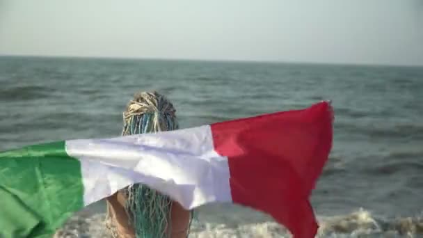 Mooie vrouw met de vlag van Italië aan zee. Sexy vrouw toerist met Italiaanse vlag op het strand — Stockvideo