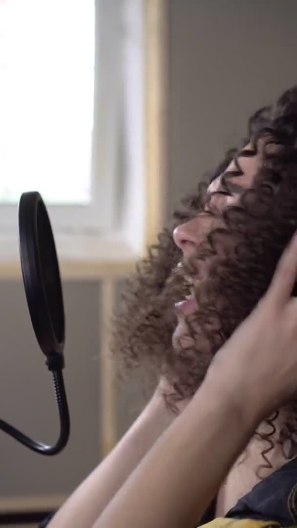 Κάθετη βίντεο: μια τραγουδίστρια σε στούντιο ηχογράφησης τραγουδά σε μικρόφωνο — Αρχείο Βίντεο