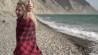 Genç, özgür, çekici bir kadın vahşi deniz kıyısında ağır çekimde koşuyor.