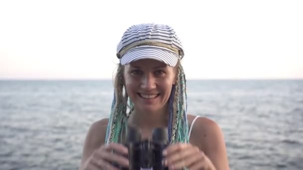 Portrait of a young happy woman with binoculars outdoors on the background of the sea — Stock Video