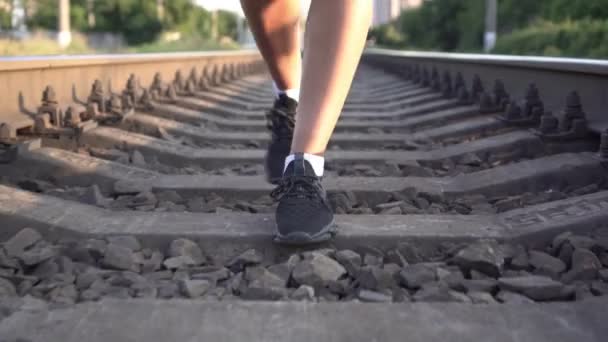 Femme marche par le chemin de fer. Les jambes des femmes marchent le long du dormeur et des rails — Video