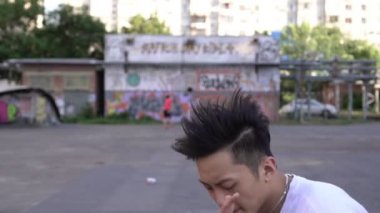 Genç Asyalı hip hop dansçısı portresi. Sokak modern dansçısı, gençlik tarzı. Adam dışarıda dans ediyor.