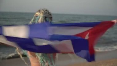 Deniz sahilinde Küba bayrağı taşıyan çekici bir kadın.