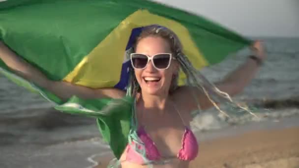 Jovem mulher atraente com bandeira brasileira na praia do mar — Vídeo de Stock