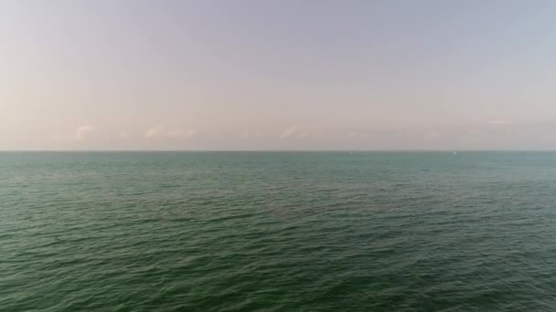 Спокойное бирюзовое море и небо с белыми облаками в солнечный день, вид с воздуха — стоковое видео