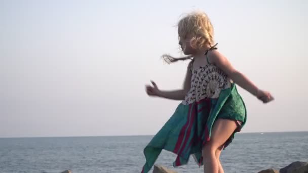 Criança feliz, menina joga uma pedra no mar — Vídeo de Stock