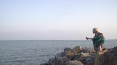 4 yaşındaki kız çocuğu okyanusa ya da sahile taş atıyor.