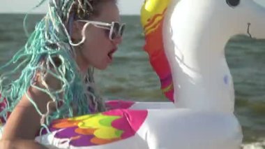 Şişme lastik çemberli neşeli komik kadın deniz sahilinde eğleniyor.