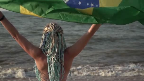 海のビーチでブラジルの旗を持つ美しい女性,スローモーション — ストック動画