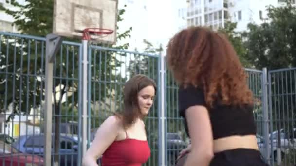 Duas jovens mulheres jogam basquete em uma quadra de rua ao ar livre — Vídeo de Stock