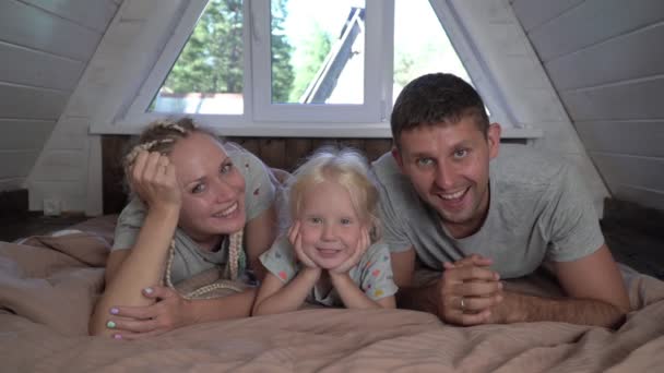 Familia feliz con una niña en casa en la cama. Padres con un hijo en casa — Vídeos de Stock