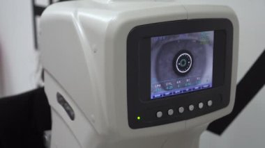 Bir göz doktoru modern ekipmanların gözlerini kontrol eder. İlaç, görüş testi