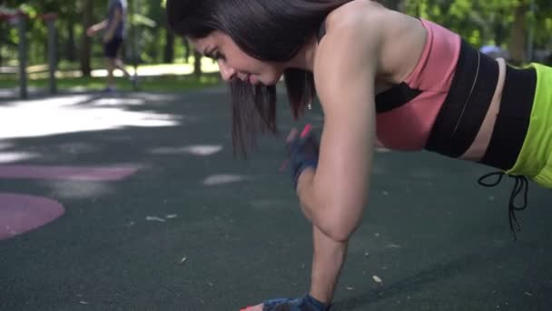 Młoda aktywna kobieta robi fitness i pompki na odkrytym boisku sportowym — Wideo stockowe