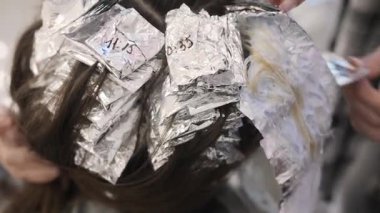 Usta renk uzmanının elleri folyodaki bukleleri temizler ve saçtaki boyayı duş suyunun basıncıyla lavaboya yıkar. Saç stilini değiştiriyorum, yakın plan.