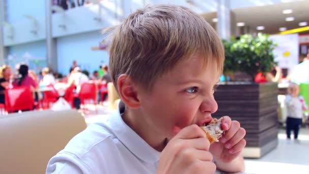 The child eats a chicken in a fast food — Stock Video