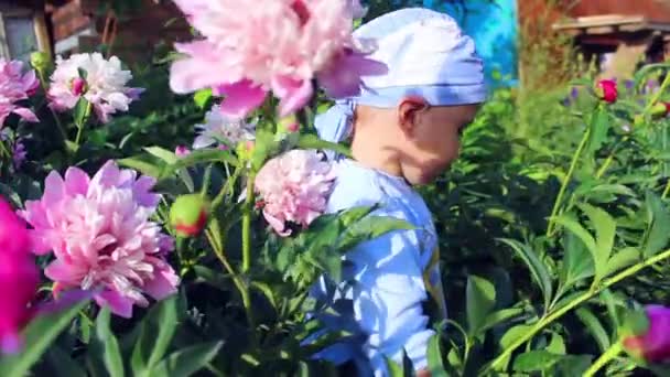 Ett barn leker i trädgård blommor — Stockvideo