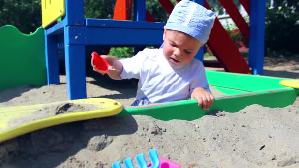 Un niño juega en la caja de arena — Vídeos de Stock