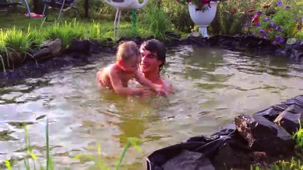 Молодой человек играл с маленьким ребенком в пруду — стоковое видео