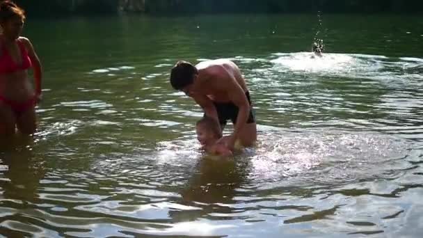 Lycklig familj spelar i vattnet med barnet — Stockvideo