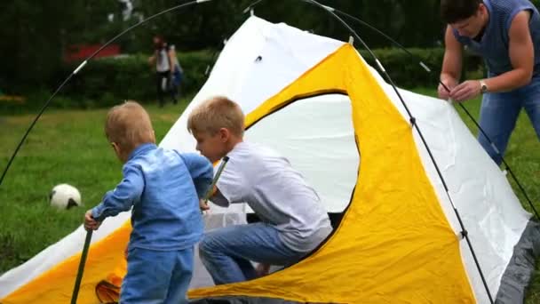 Un homme avec des enfants rassemblant tente — Video