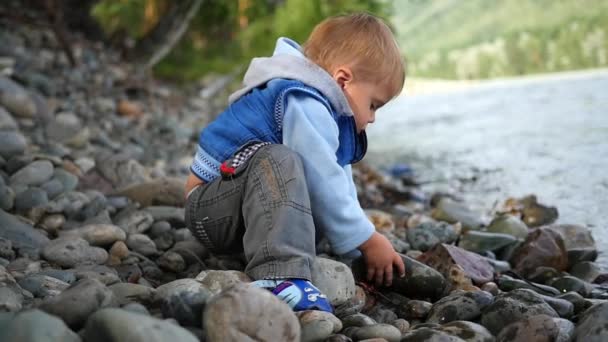 Ребенок бросает камни в реку — стоковое видео