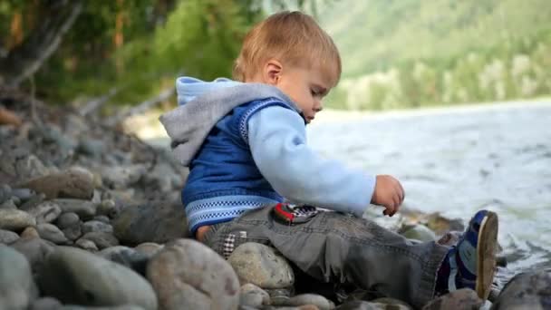 Niño arrojando piedras al río — Vídeos de Stock