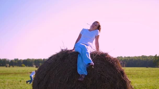 Girl resting on a haystack at sunset — Stock Video