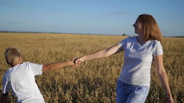 Una chica con un niño girando en un campo — Vídeos de Stock