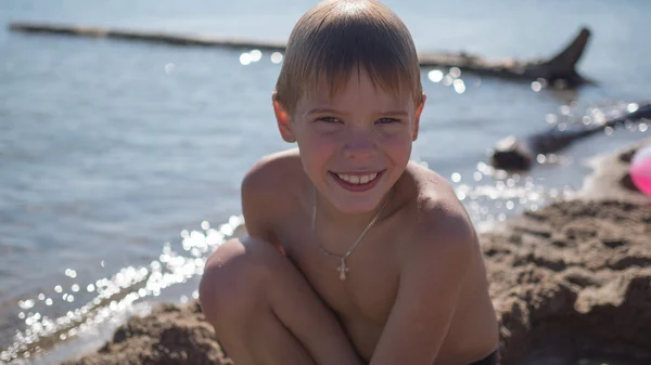 Ευτυχισμένο παιδί χαμογελώντας στην παραλία κοντά στο νερό — Φωτογραφία Αρχείου