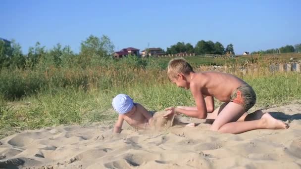 Niños jugando en la playa con arena — Vídeo de stock
