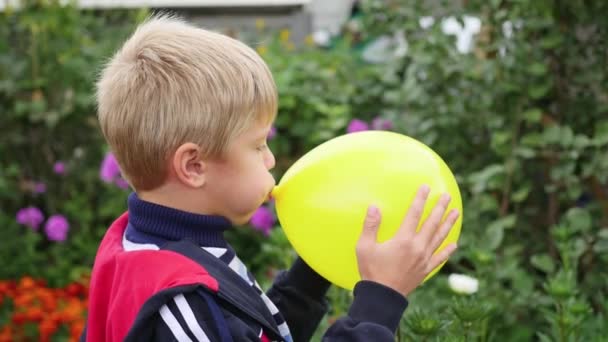 Criança no jardim inflar um balão amarelo — Vídeo de Stock