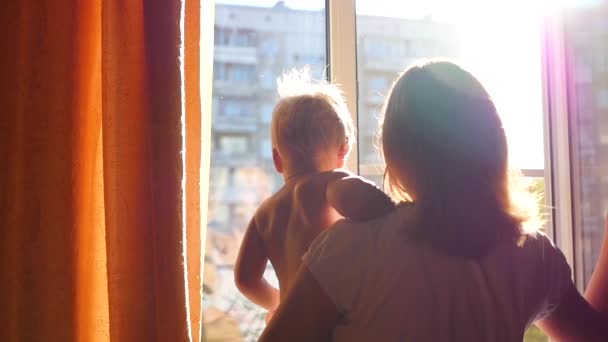 Una chica con un niño mirando por la ventana — Vídeos de Stock