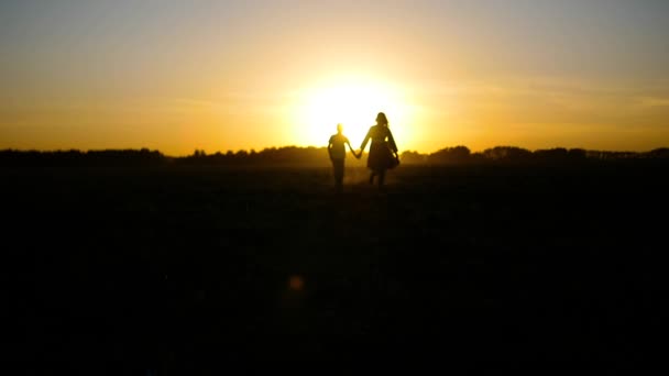 El chico con la chica corriendo hacia el atardecer — Vídeos de Stock