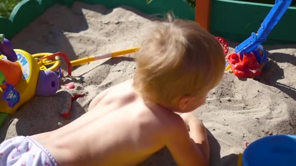 Un niño juega en la caja de arena — Vídeos de Stock