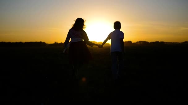 El chico con la chica huyendo hacia el atardecer — Vídeos de Stock