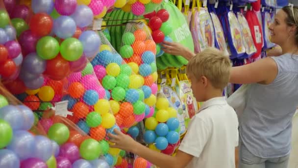 NOVOSIBIRSK, RÚSSIA - 31 de julho de 2016: uma criança em uma loja de brinquedos olhando para um produto — Vídeo de Stock