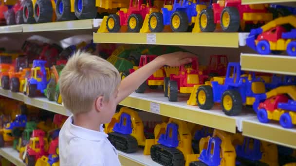 Un niño en una juguetería mirando un coche — Vídeos de Stock