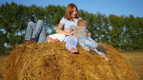 Moeder met kinderen spelen op een hooiberg — Stockvideo