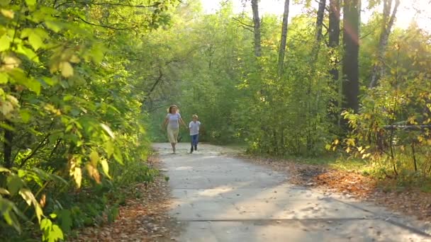 Mujer con un niño corriendo por un sendero en un parque cogido de la mano — Vídeos de Stock