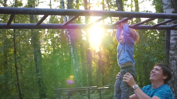 El padre ayuda al niño a subir en la escalera horizontal — Vídeos de Stock