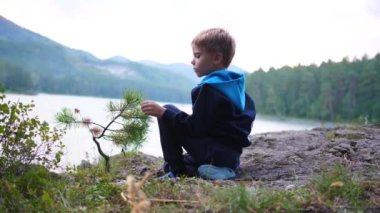 Bir çocuk nehir kıyısında bir uçurumda oturuyor. Akşam vakti.