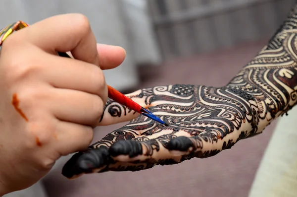 Молодая женщина-мехенди художник рисует хну на руке — стоковое фото